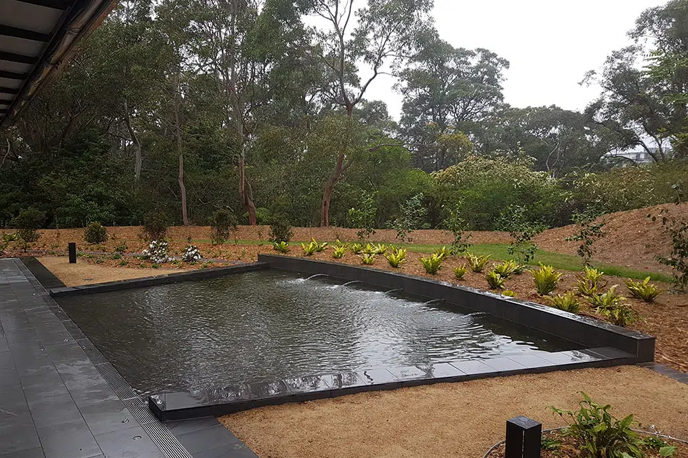 Peaceful cemetery pond surrounded by trees and landscaped gardens.